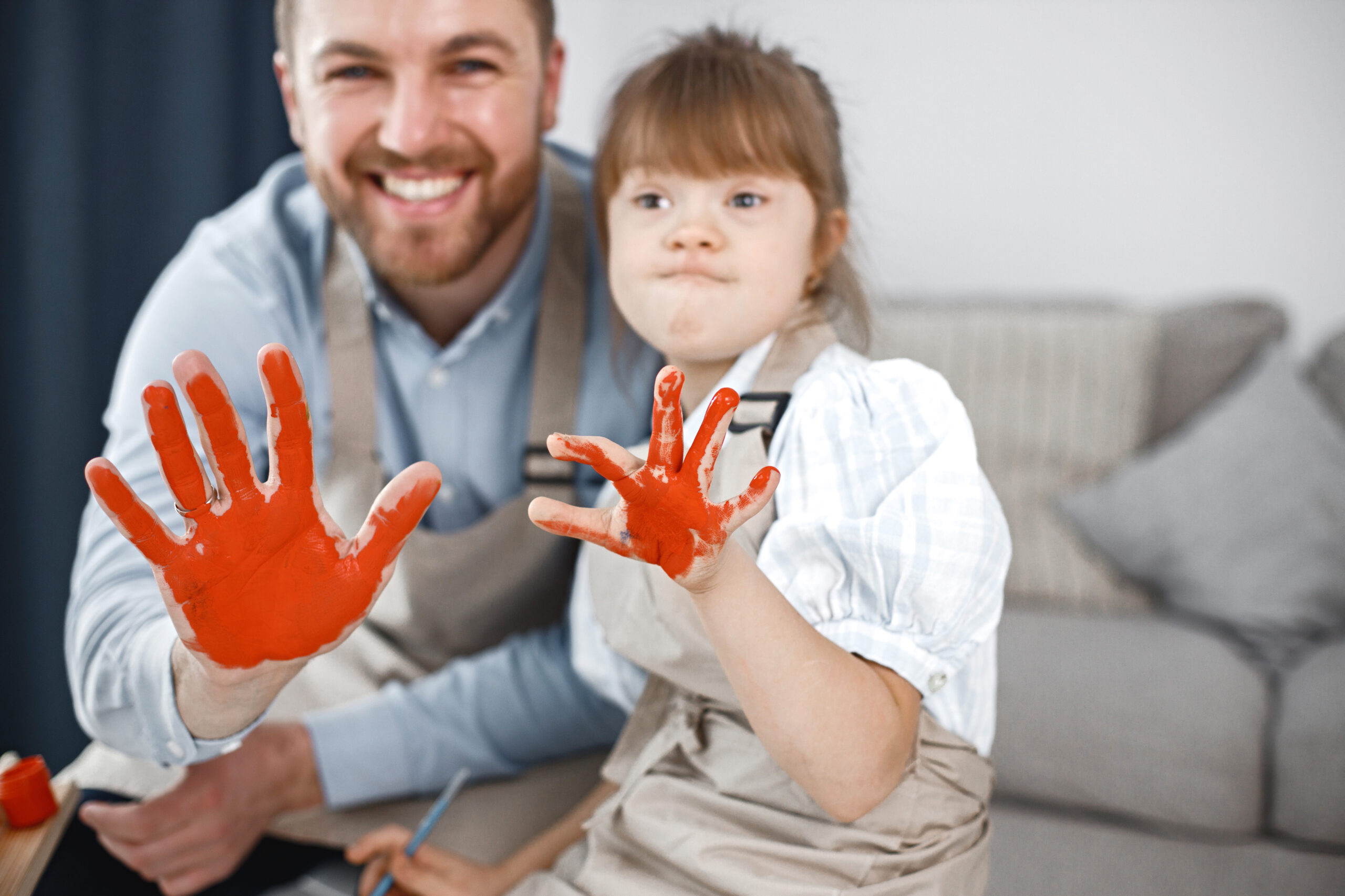 girl with down syndrome and her father painted hands in red colo